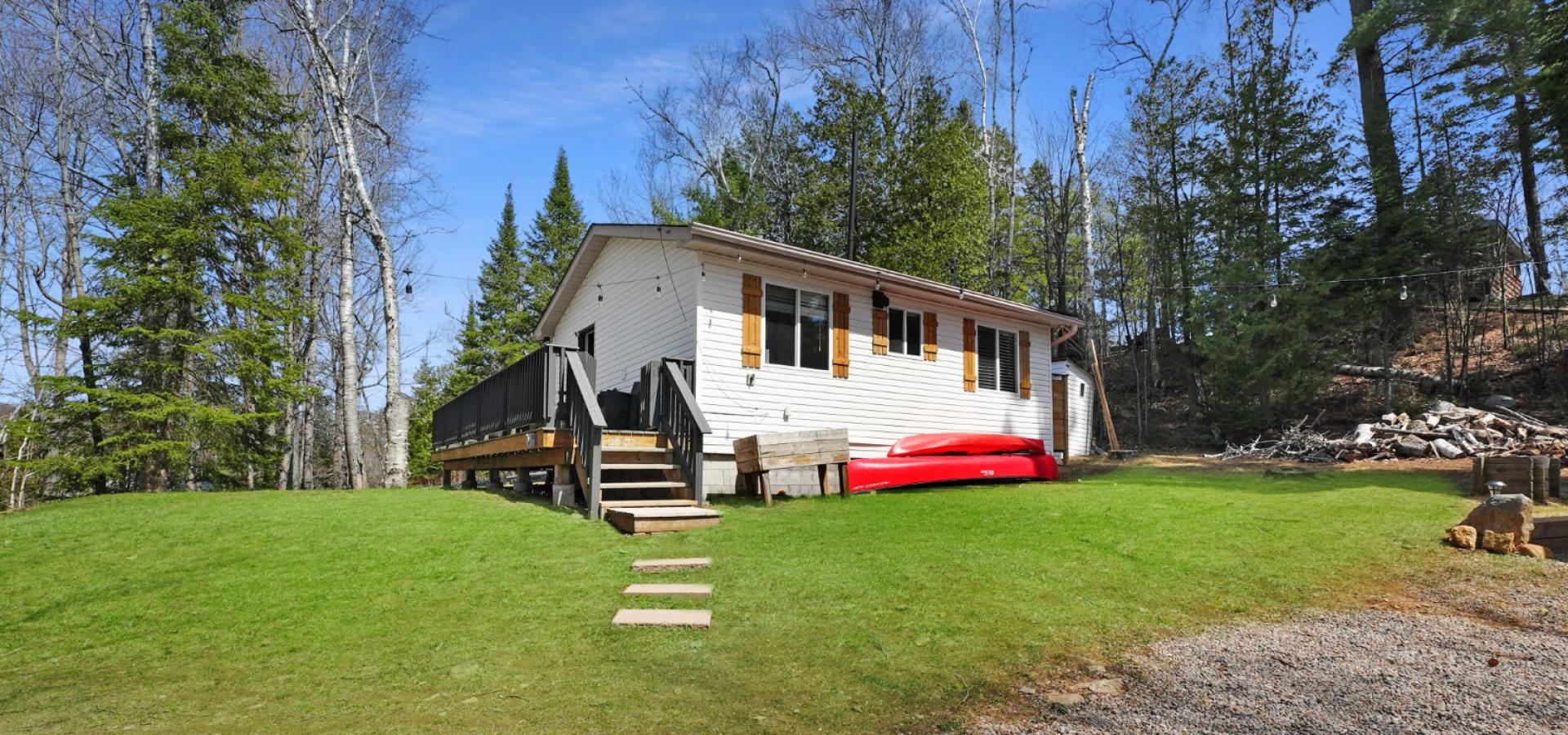 White home with red canoe, grass and stairs leading up