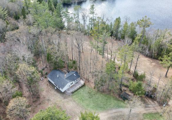 Aerial view of a home with trees surrounding it and facing the lake