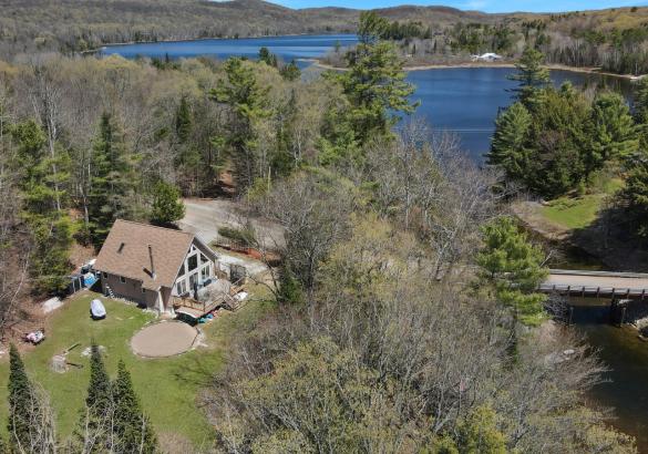 Aerial view of a property with trees, a road, a river and a lake in the background