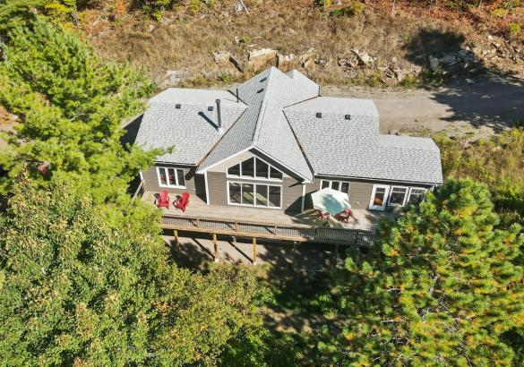 Aerial view of a cottage with large windows and trees