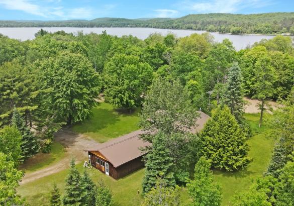 House surrounded by trees with a river leading to the lake.