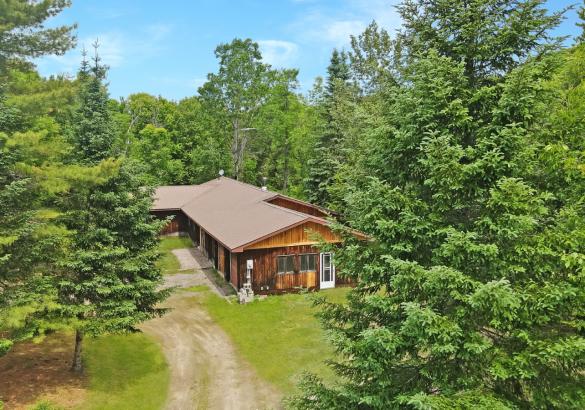 Aerial view of a cottage with trees around it
