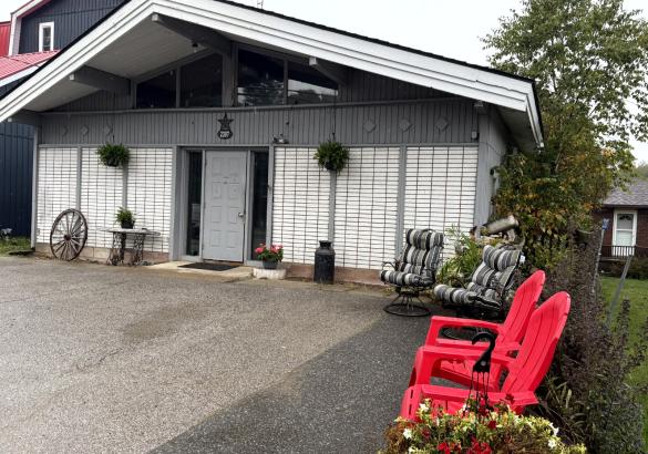 White and grey home with 2 red muskoka chairs and 2 striped chairs sitting out front.